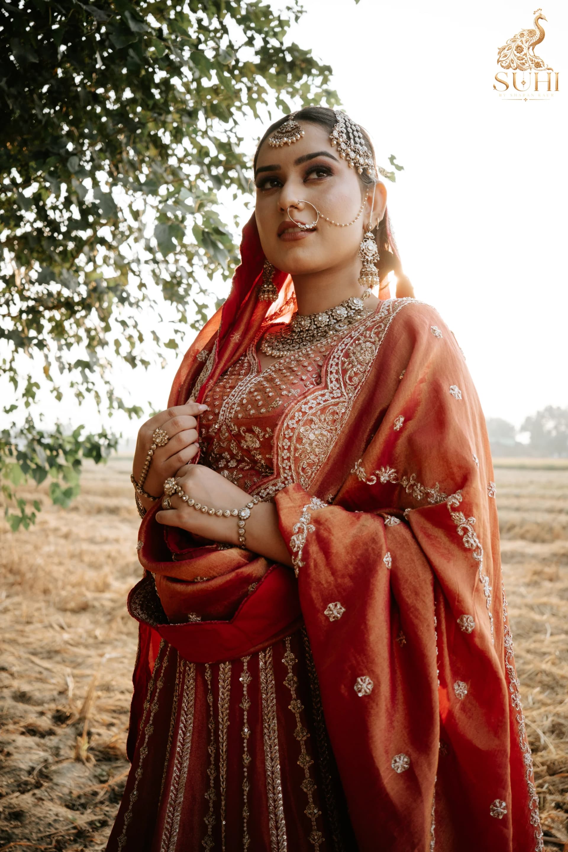 Portrait of bride in MEHRUNISA, draped in a richly embroidered royal red veil